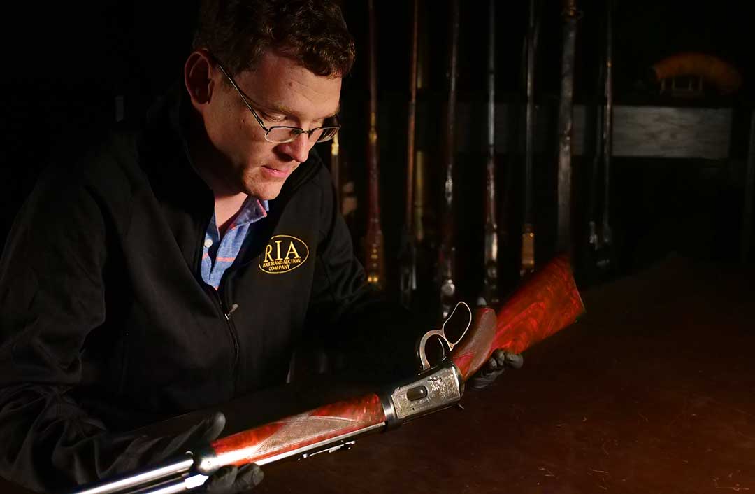 Rock-Island-Auction-Company-Describers-Team-Lead-Andrew examines a Winchester Deluxe Model 1894 Takedown Rifle