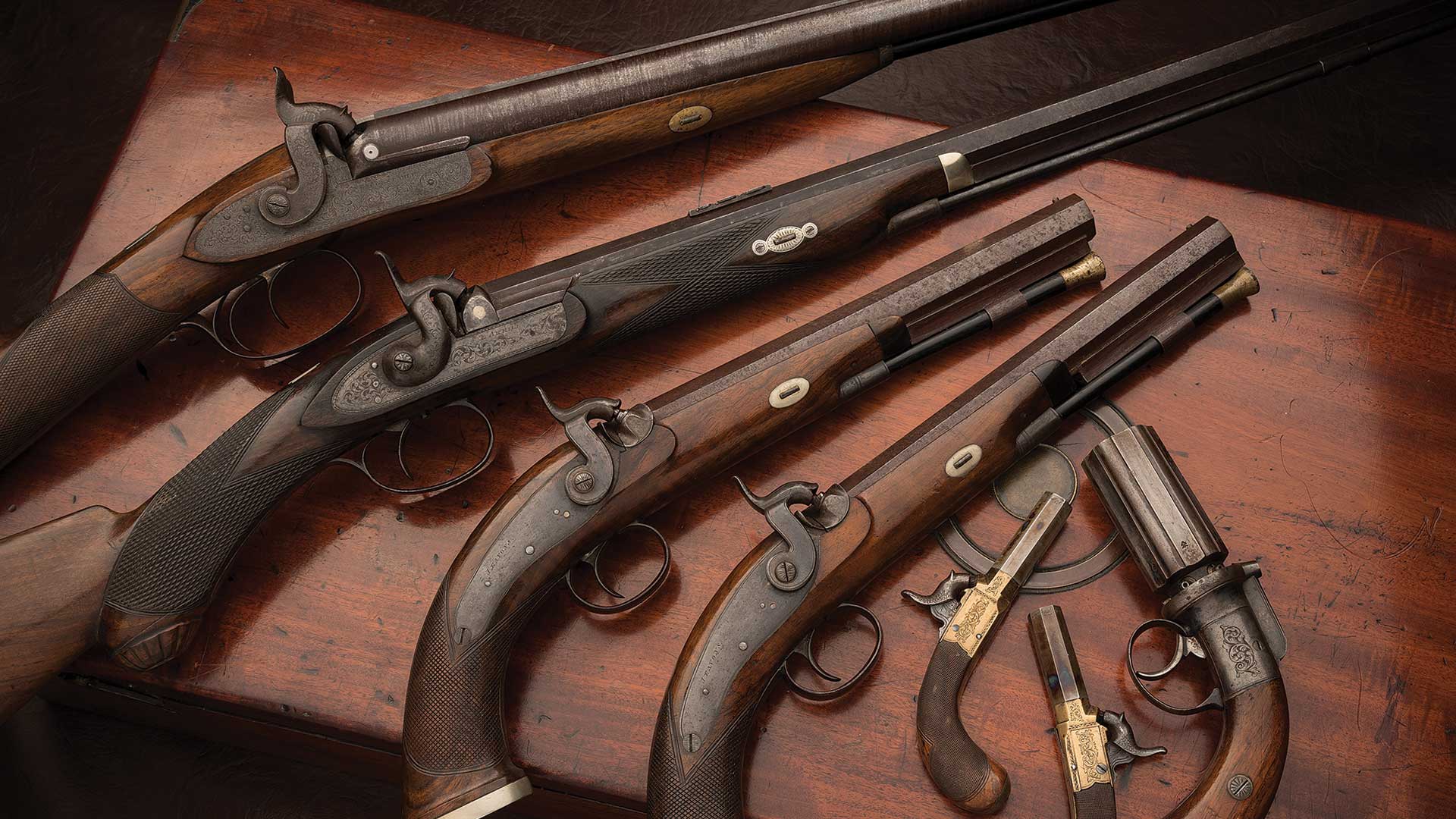 Incredibly-scarce-cased-seven-piece-garniture-of-engraved-English-percussion-firearms