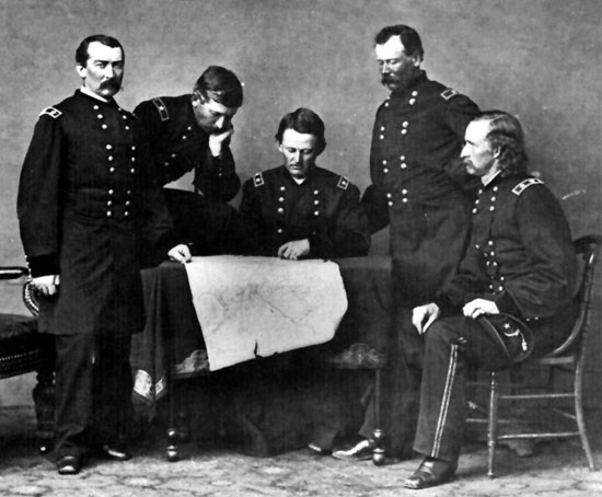 From left: Sheridan, Forsyth, Merritt, Devin and Custer. All the men are gathered around a table looking at plans.
